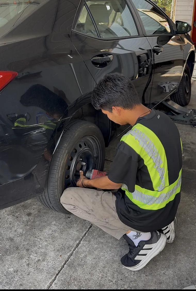 Crew member in a safety vest installing a tire